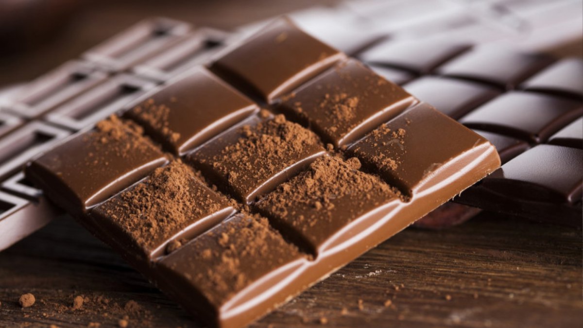 Под шоколадку. Шоколад на деревянном столе. Текстура шоколадного батончика. Шоколадный батончик из темного шоколада.
