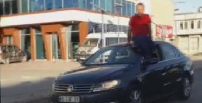 Otomobilin tavanına oturup, direksiyonu ayağıyla kontrol ederek araç kullandı