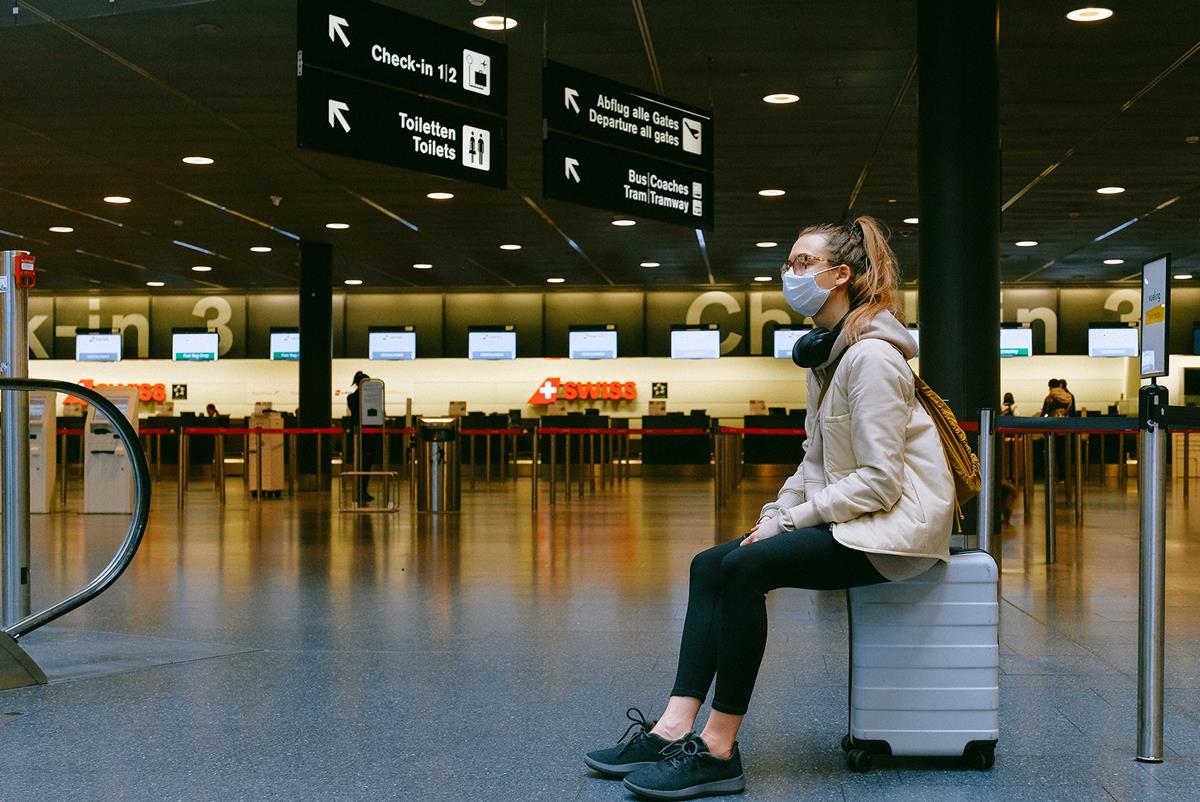 woman-sitting-on-luggage-mask-pexels