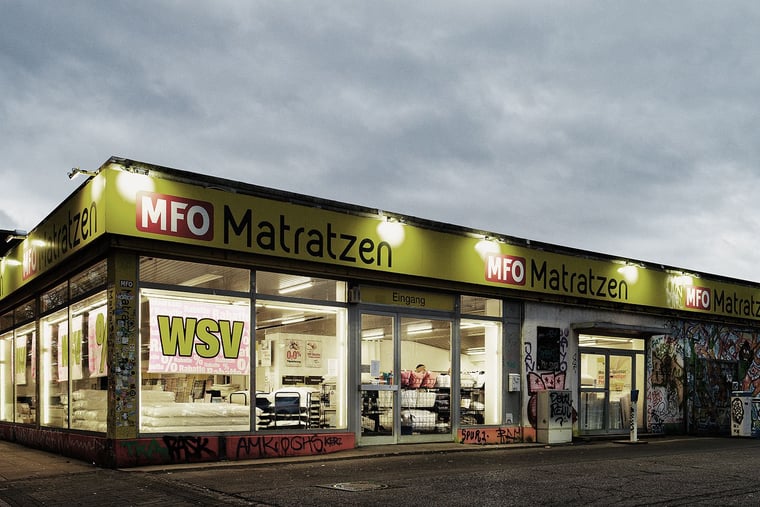 gebaeude-der-filiale-von-mfo-matratzen-in-koeln-ehrenfeld-beleuchtetes-gebaeude-der-filiale-von-mfo-mat